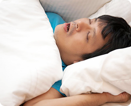 睡眠時無呼吸症候群（SAS）のイメージ｜白い布団と枕に包まれた男性が仰向けで眠っている写真
